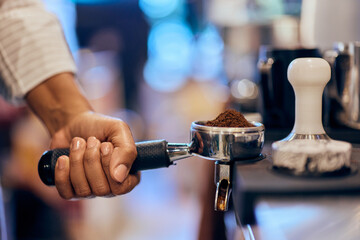 Fototapeta na wymiar Side view of a female bartender making a coffee cup, ground coffee into the handle.
