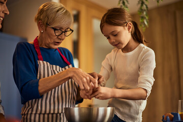 Three generations in the kitchen, a little girl, helping her grandma and her mother.