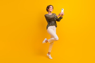 Full length photo of funky cool charming blogger girl wear trendy clothes recording video blog isolated on yellow color background