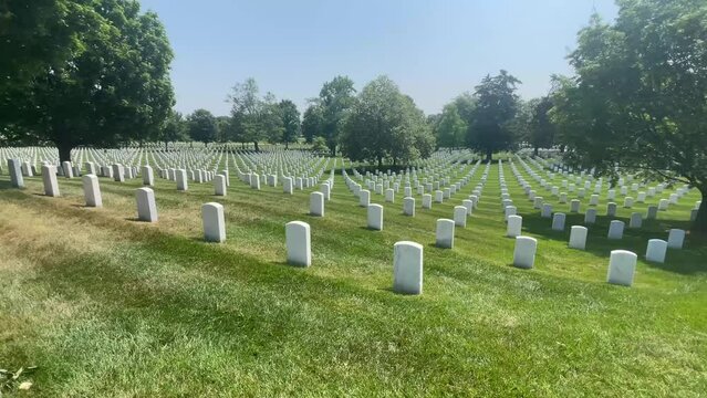 Walking on a sunny day with huge rows of white marble tombstones at Arlington National Military Cemetery in Washington DC, the capital of the USA.