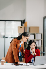 Two Asian businesswoman and man discuss investment project working and planning strategy with tablet laptop computer in modern office..