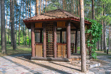 A gazebo made of wooden logs for relaxing in the forest and protection from sunlight and rain. A...