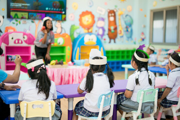 Rearview of elementary school children participating in a class activity with their teacher.