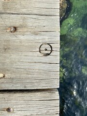 Part of a wooden dock with a circle with a dot sign. Greenish water. Old wood texture. Dot middle of a circle sign, symbol of Spirit and Matter. The point in a circle. Unity symbol. Dotted circle.