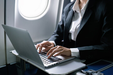 businesswoman flying and working in an airplane in first class, sitting inside an airplane using...