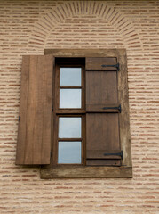 New arched window with one open wooden shutters on brick wall closeup