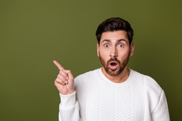 Photo of surprised nice man open mouth dressed stylish white clothes presenting empty space banner isolated on khaki color background