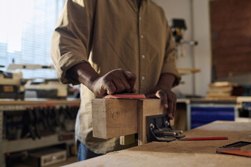 Close up of unrecognizable senior craftsman polishing wood building furniture in sunlit workshop