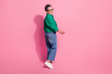 Full body photo of attractive pensioner woman walking turn around back wear trendy green clothes isolated on pink color background