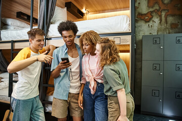 happy african american student using mobile phone near multiethnic friends in youth hostel - obrazy, fototapety, plakaty