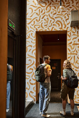 back view of young couple of students with backpacks in corridor of hostel with modern design