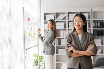 Asian businesswoman is discussing a new business project on a tablet. In a meeting, two people discuss investment projects on data charts and planning strategies. About new business