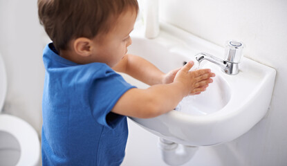 Child, boy and water for washing hands in bathroom, hygiene and prevention of germs or bacteria at home. Male person, kid and learning at basin or cleaning and sanitary, liquid soap and disinfection
