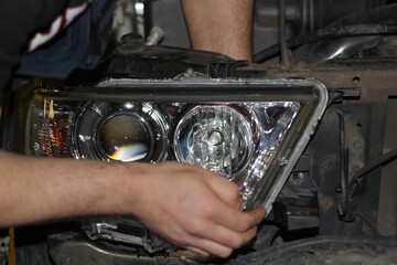 The car mechanic installs the lens in the headlight housing. The concept of a car service....
