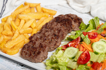 Grilled meat balls. Grilled meatballs with salad and fries on a white background