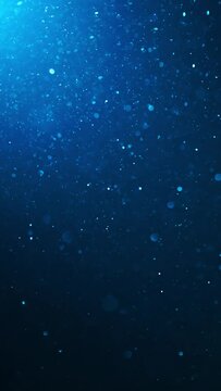 Vertical shot blue glitter background shot in slow motion. Underwater particles flying and shining in spotlight, shot with depth of field. Space dust beautiful bokeh abstract background	
