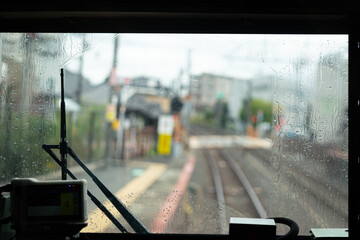 Close-up at train front windscreen with water droplet of surface with railway track and city environment as blurred background. Transporation vehicle scene photo, selective focus.