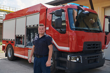 A confident firefighter strikes a pose in front of a modern firetruck, exuding pride, strength, and preparedness for emergency response