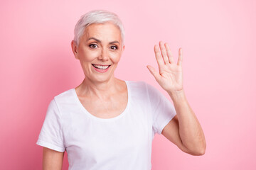 Photo portrait of pretty retired female waving palm say hi wear trendy white outfit isolated on...