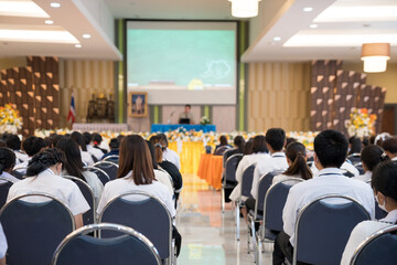 Rearview of university students attending academic conference presentations in the auditorium.