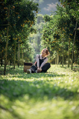 A happy woman farmer is resting in orchard or orange farm.