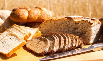Lot of different flavored bread, wheat, rye, on the table in the field outside