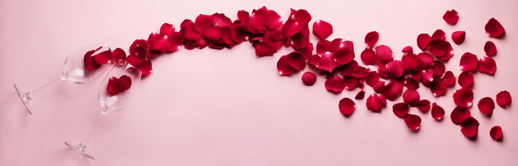 Rose flower petals and flute glass flat lay on pink background