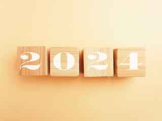 Wooden blocks with the Year number 2024 on a peach colored paper background, Happy New Year concept photograph