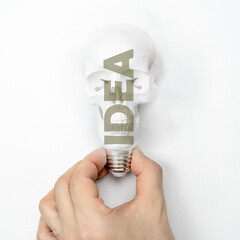 Man holding a skull in the form of a light bulb with idea text. Concept of unsuccessful or fatal...