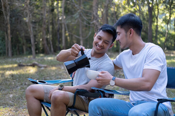 Asian LGBTQ couple drinking coffee in a romantic camping tent. LGBTQ couple drinking coffee in a camping tent, enjoying nature, forest, camping atmosphere, LGBTQ, gay, gay men.