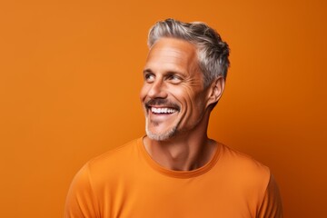 Portrait of a happy mature man on orange background. Copy space.