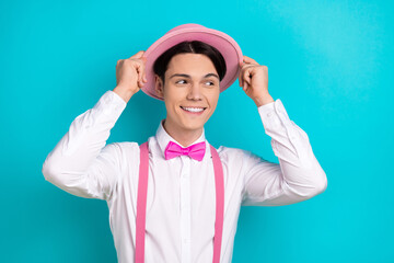 Photo of attractive young man look empty space touch headwear dressed stylish pink clothes isolated on aquamarine color background