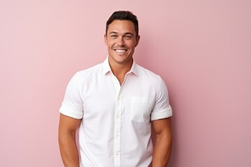 Portrait of a handsome young man smiling and looking at camera against pink background