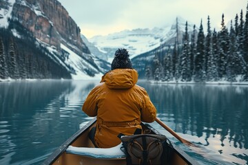 Male traveler in winter coat canoeing in Lake. - obrazy, fototapety, plakaty