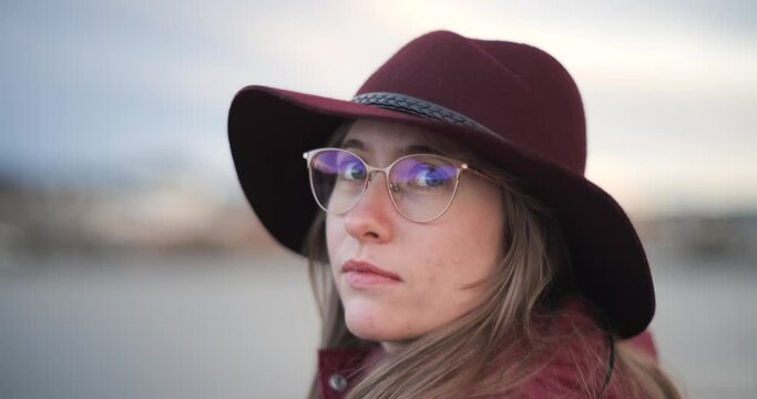 Young woman wearing glasses and a stylish hat, close up shot, subtle smile, shallow depth of field