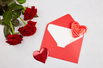 A bouquet of red roses, a red envelope with an empty piece of paper for congratulations or a declaration of love on a grey isolated background. Valentine's Day, Mother's Day, Birthday.