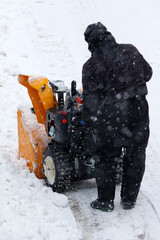 Homme avec une souffleuse à neige sur la route lors d'une chute de neige - 707186348
