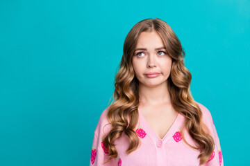 Portrait photo of young funny sad stunning girl grimacing looking empty space in bad mood deciding isolated on blue color background