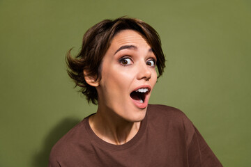 Portrait of ecstatic funny girl with short hairstyle wear oversize t-shirt staring at big discount isolated on green color background