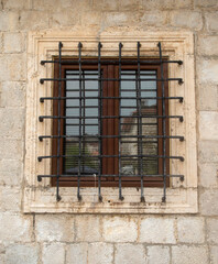 Fototapeta na wymiar Old window with metal grill on stone facade in Montenegro