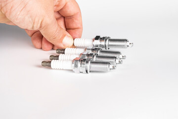 A new candle in a man's hand on a white background. The concept of choosing spark plugs.