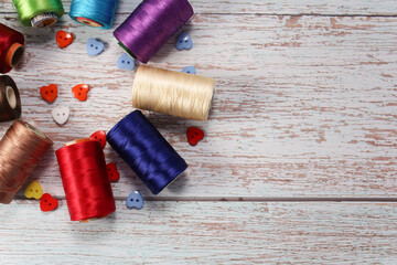 A set of colored threads for sewing clothes, on a wooden background