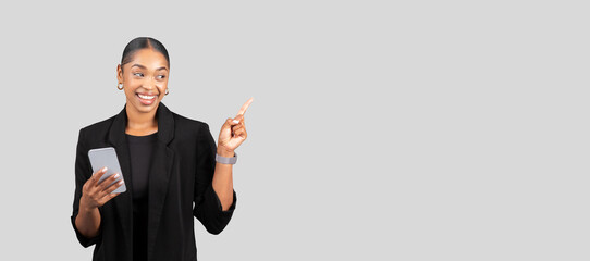 Confident African American businesswoman with a smartphone pointing upwards