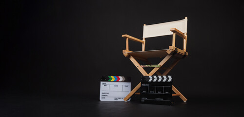 Two clapper board with white director chair on black background..