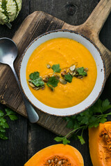 Pumpkin soup and organic pumpkins on wooden table. Seasonal autumn food - Spicy pumpkin soup in...