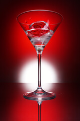 Martini glass with rose in ice on bright red background