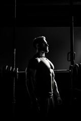 Fototapeta na wymiar Muscular man practicing fitness in the gym using barbells