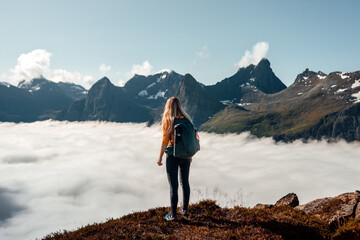 Woman tourist hiking alone in mountains Norway, girl backpacker enjoying clouds view adventure vacations healthy lifestyle outdoor
