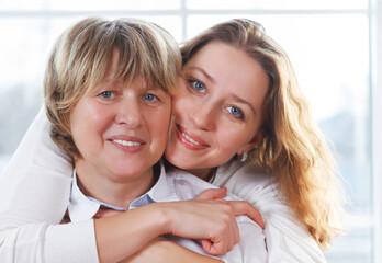 Close up portrait of a mature mother and adult daughter being close and hugging