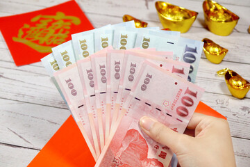 Spring Festival couplet, red envelopes and money on the table. Concept for Chinese New Year and lucky money. The words on couplets are used to pray for wealth.